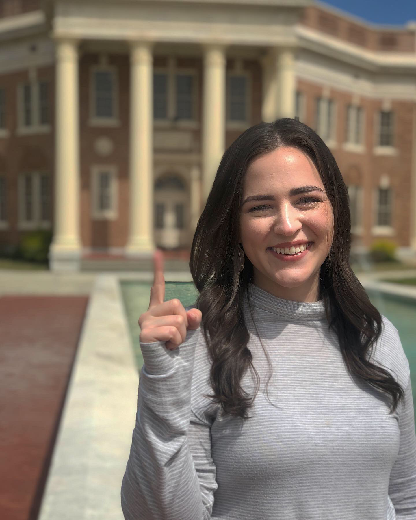 A person pointing up in front of a building  AI-generated content may be incorrect.